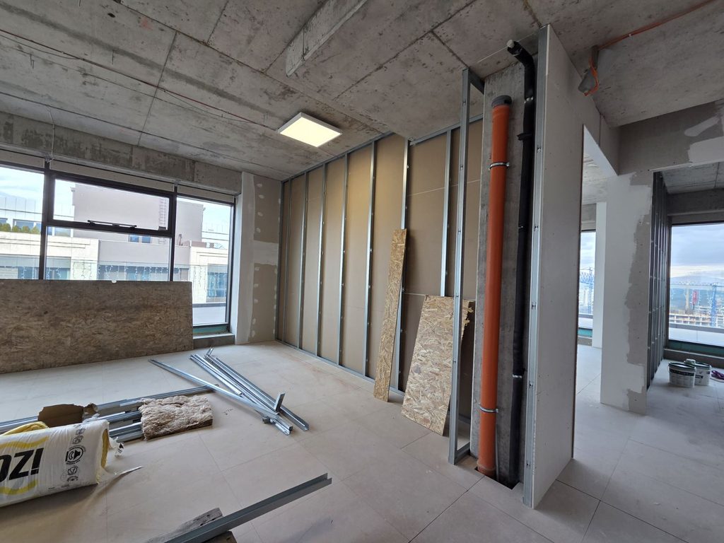 Architect and project manager reviewing drawings during an office construction site visit.